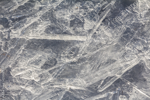 Cracked ice on the frozen surface of the lake. Winter patterns on ice water