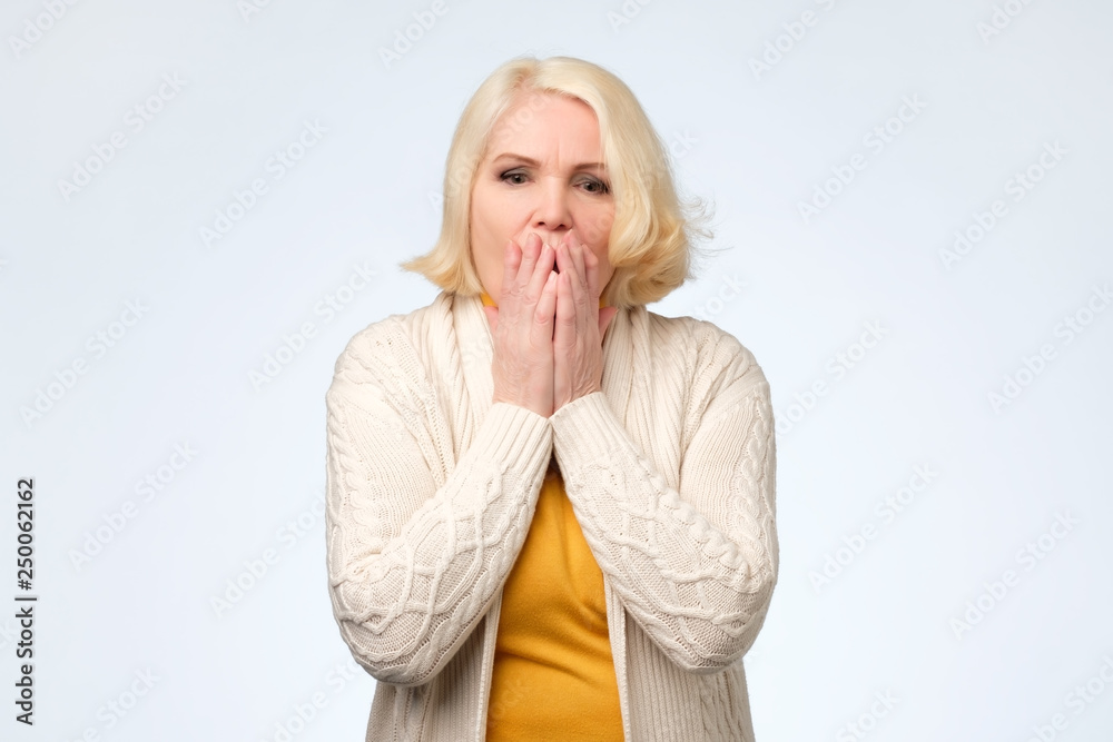 Senior woman covering face with hands, her eyes full of terror and panic Senior woman covering face with hands, her eyes full of terror and panic
