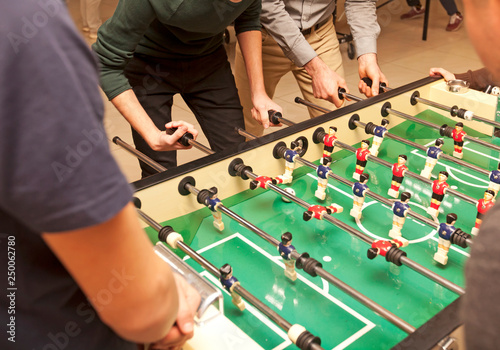 Guys are  playing table soccer indoor photo