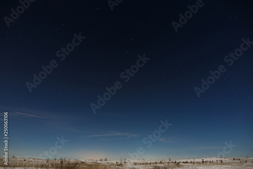 Stars in the night sky over the snow-covered plain. The background of deep space is photographed under the full moon.