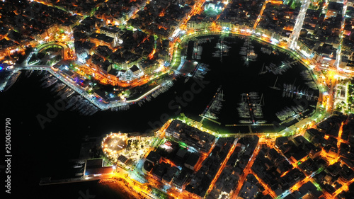Fototapeta Naklejka Na Ścianę i Meble -  Aerial drone night shot of dazzling illuminated safe port of Marina Zeas with luxury yachts and sailboats docked in the heart of Piraeus, Attica, Greece