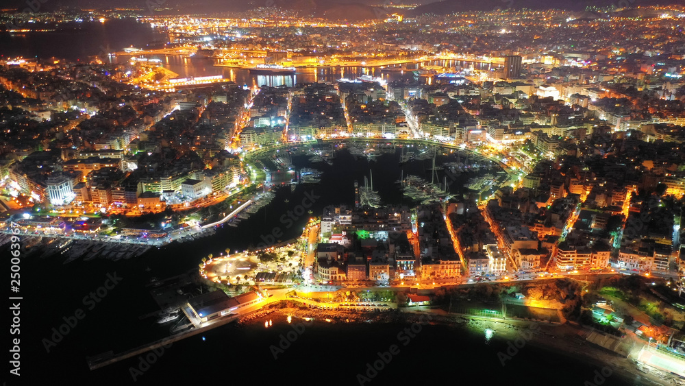 Aerial drone night shot of dazzling illuminated safe port of Marina Zeas with luxury yachts and sailboats docked in the heart of Piraeus, Attica, Greece