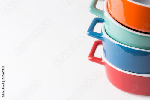 Canvas Print Stack of orange and turquoise ceramic cocottes on white wood table