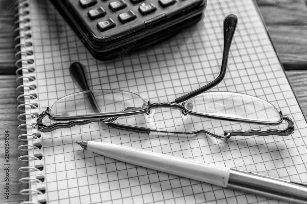 Pen, eyeglasses and calculator on notebook. Close up, study, business and education concept. Image slightly blurred on foreground and background Pen, eyeglasses and calculator on notebook. Close up, study, business and education concept. Image slightly blurred on foreground and background