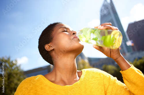 Close up healthy young black woman drinking water outdoors in park