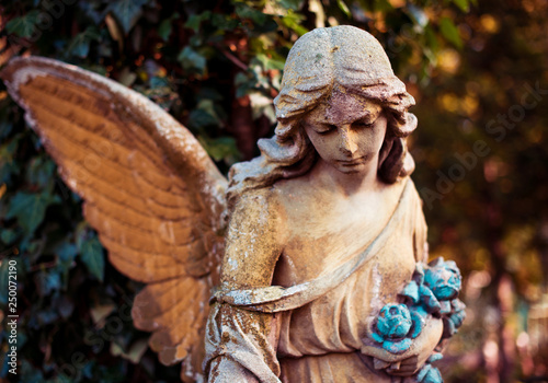 Obraz na płótnie A fragment of ancient sculpture angel in a golden glow in the old cemetery. Symbol of love, invisible forces, purity, enlightenment, ministry. Chariot. Retro vintage style. w salonie
