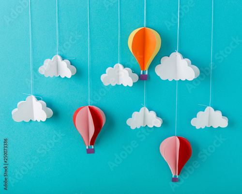 Blue background paper with white clouds on a string and balloons, minimalism