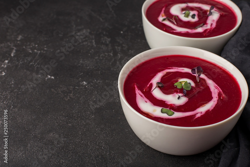two plates with beetroot soup and sour cream on black background