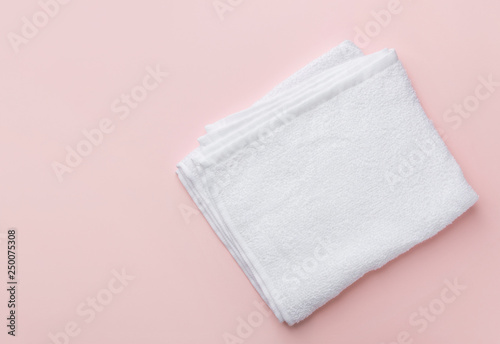 Folded clean white fluffy terry towel on pastel pink background. Minimalist flat lay. Women's baby hygiene laundry body care wellness well-being concept. Copy space