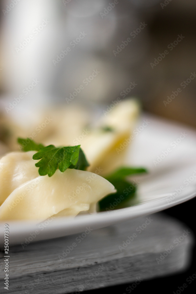 Traditional russian pelmeni, ravioli, dumplings with meat on dark concrete background. Parsley, pepper, and spices. Traditional russian pelmeni, ravioli, dumplings with meat on dark concrete background. Parsley, pepper, and spices.