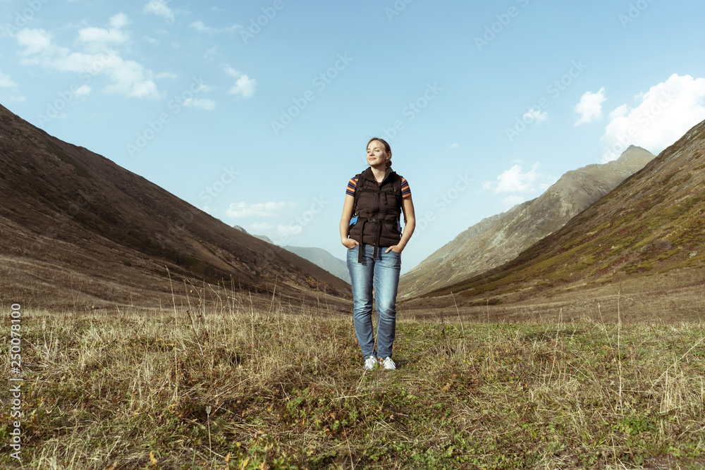 girl full-length in the mountains with a backpack