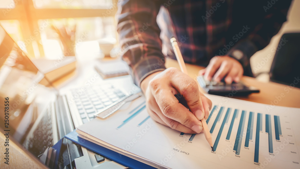Working process startup. Businessman working at the wood table with new finance project. Modern notebook on table. Pen holding hand Working process startup. Businessman working at the wood table with new finance project. Modern notebook on table. Pen holding hand
