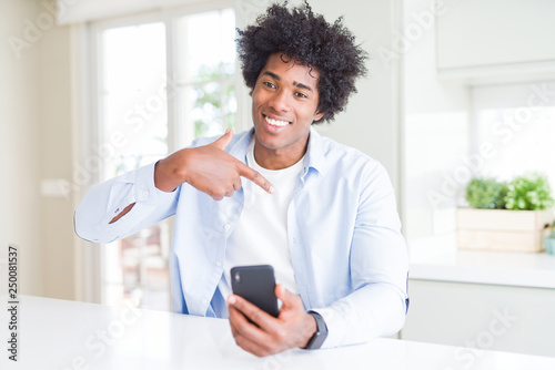 African American man using smartphone with surprise face pointing finger to himself