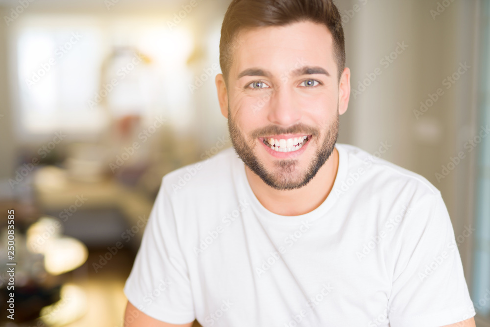 Young handsome man wearing casual white t-shirt at home with a happy and cool smile on face. Lucky person.