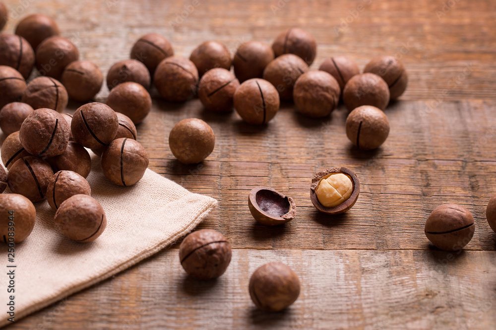 Macadamia nuts on a wooden background. A lot of macadamia nuts in a closed shell. Macadamia nuts. Macadamia nuts on a wooden background. A lot of macadamia nuts in a closed shell. Macadamia nuts.
