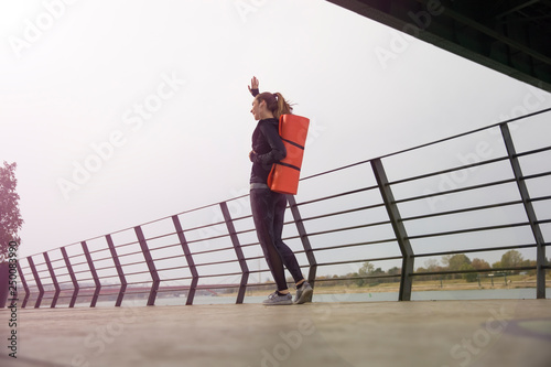 Fitness woman walking with mat on back