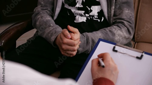 Young worried teenager at the psychologist for counseling - closeup on hands, camera slide and refocus