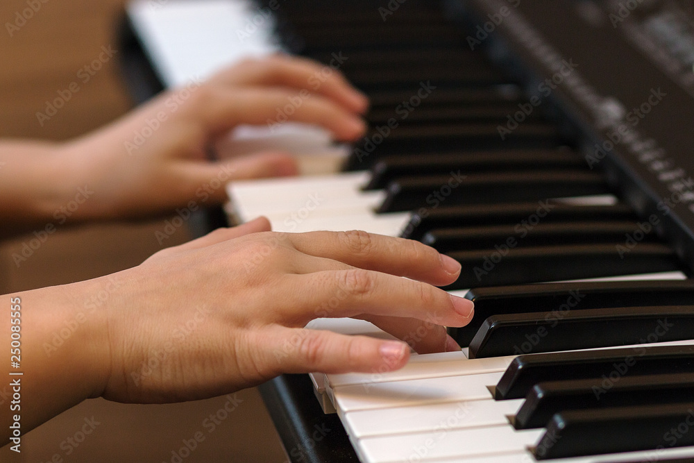 Hands of the child on the piano keys. Selective focus. Hands of the child on the piano keys. Selective focus.