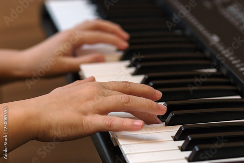 Hands of the child on the piano keys. Selective focus.