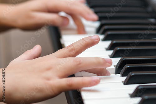 Hands of the child on the piano keys. Selective focus.