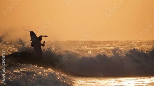 Surfer jumping during a sunset at a surfspot in Bali. Full HD footage in slow-motion. photo