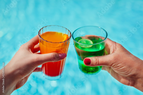 Women holding cocktails on swimming pool background. All inclusive