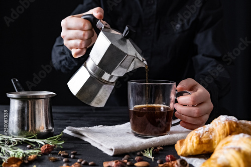 Pouring coffee from an italian percolator, shot in low key. Male hands pour black coffee from italian moka brewer