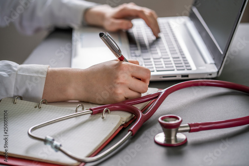 Workplace of doctor with laptop and stethoscope and notebook on the desk white top view shot