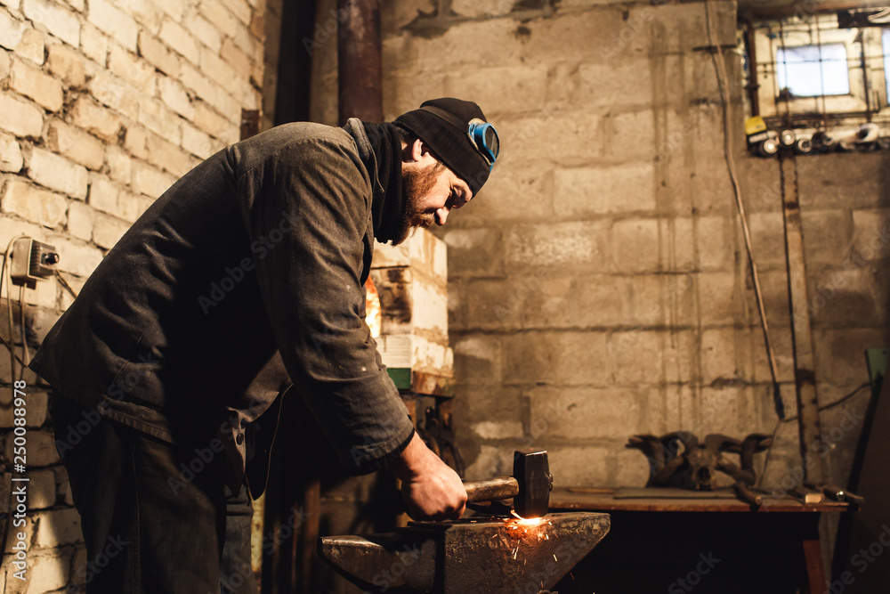 The blacksmith manually forging the red-hot metal on the anvil and flying sparks. The blacksmith manually forging the red-hot metal on the anvil and flying sparks.
