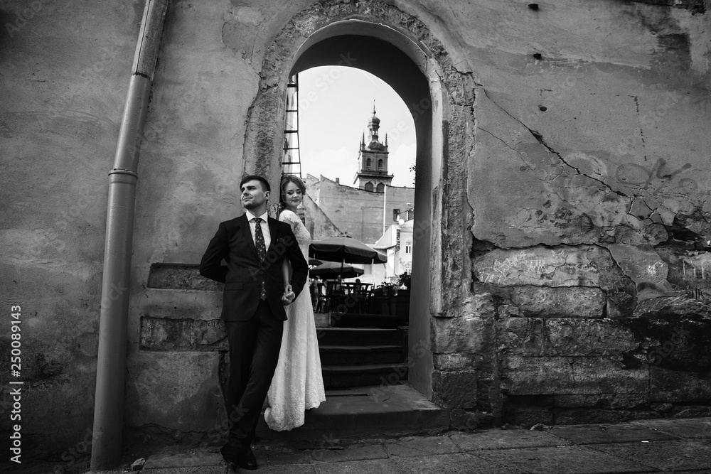 elegant wedding couple posing in old european city street. beautiful view at buildings. luxury bride and groom standing. romantic sensual moment. black white photo