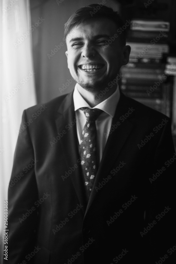 stylish groom laughing in morning room, getting ready for big day. preparation to wedding ceremony. happy man. black white photo stylish groom laughing in morning room, getting ready for big day. preparation to wedding ceremony. happy man. black white photo