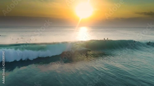 Aerial shot of a surfer surfing a perfect barrel during a sunset. 4k footage in slow-motion. photo