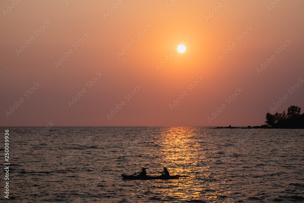 silhouette of a couple on kayak on the sea at sunset