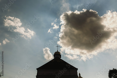 Top of christian church, golden cross on top of orthodox chapel, blue skies and white clouds in background