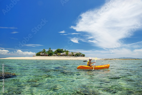 Young woman kayaking near South Sea Island, Mamanuca islands group, Fiji photo