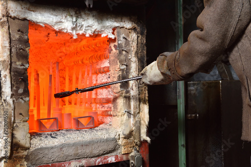Valokuva Worker pulls out the heated parts with tongs from an electric furnace for hardening metal