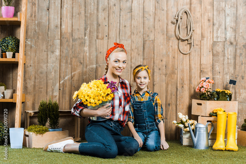 happy woman holding flowers and sitting with cute daughter on grass © LIGHTFIELD STUDIOS