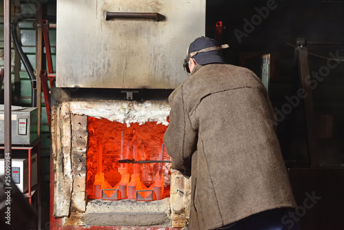 Fotografia A man is a worker, pulls out the hot parts from an electric furnace for hardening metal