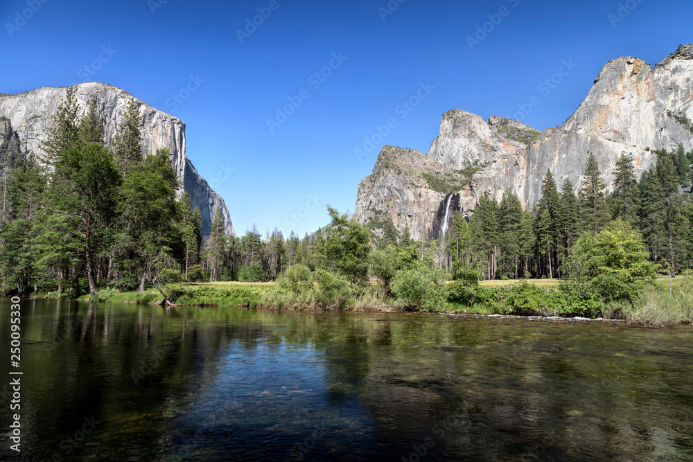 Iconic features of the amazingly beautiful Yosemite Valley are viewed from the bank of California’s Merced River.