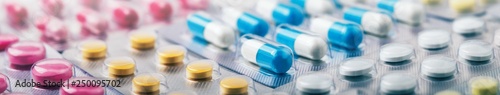 Heap of medical pills in white, blue and other colors. Pills in plastic package. Panoramic banner for design.