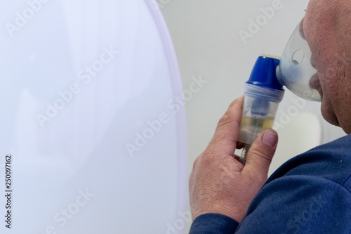 The man put on a transparent inhaler mask on the lips and nose to breathe medicinal vapors. Treatment of the respiratory tract and pulmonary system. Inhalation Equipment in the hospital. Copy space.