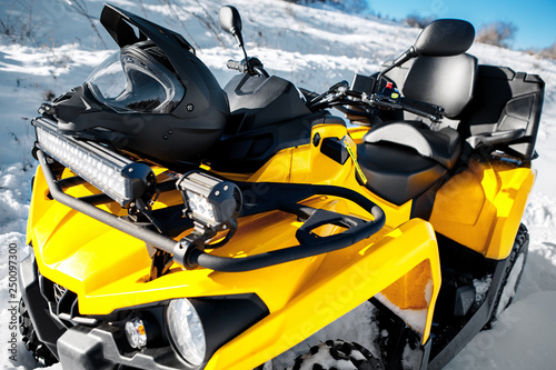 Close-upphoto of yellow ATV 4wd quad bike stand in heavy snow with deep wheel track.