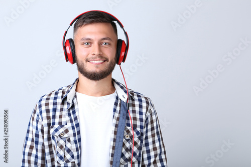 Young man with red headphones on grey background