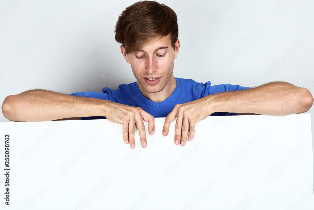 Beautiful young man holding blank board on grey background Beautiful young man holding blank board on grey background