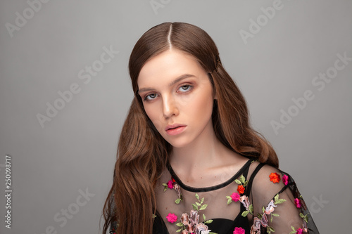 Portrait of a beautiful European fashion model on a gray background.