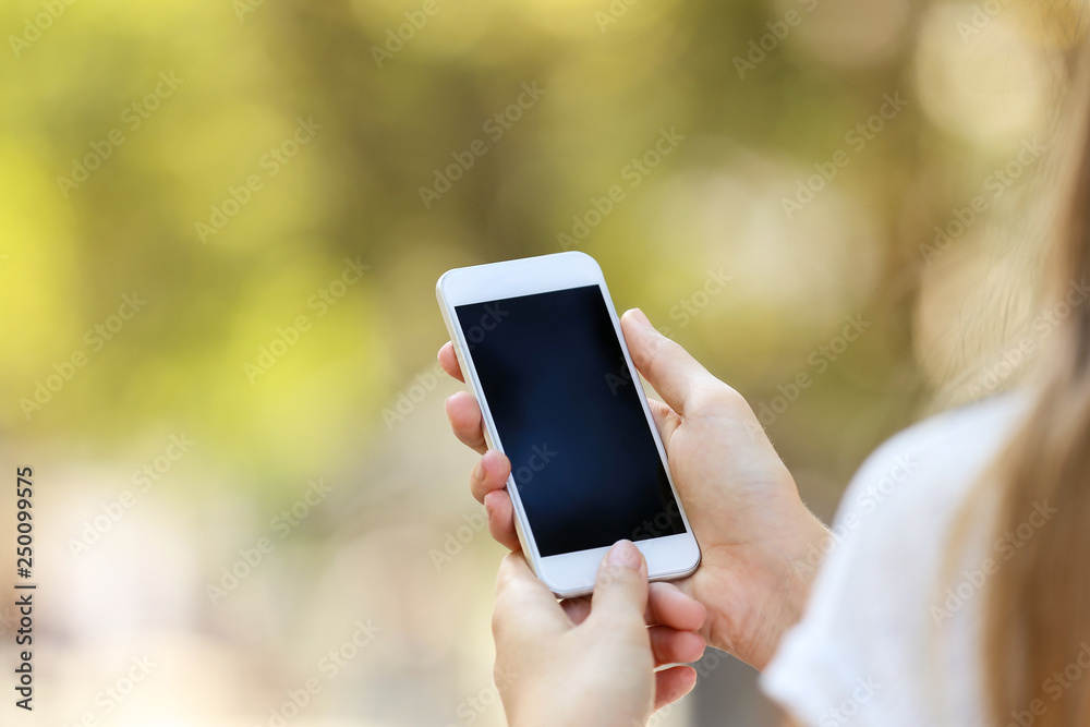Woman holding and using smartphone on blurred background