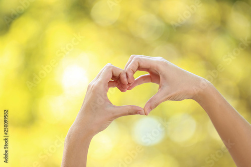 Female hands in shape of heart on blurred background