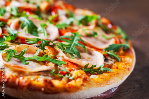 Pizza with Mozzarella cheese, mushrooms, ham, tomato sauce, pepper, Spices and Fresh arugula. Italian pizza on wooden table background 