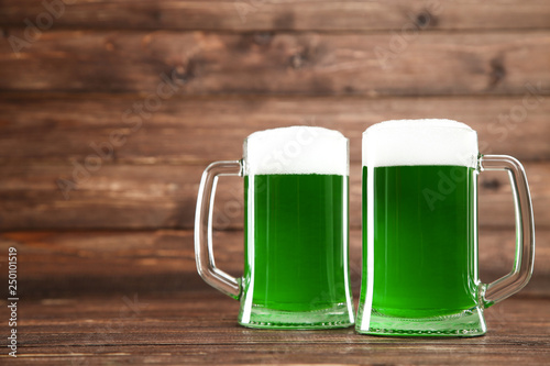 St. Patrick's Day. Glass mugs with green beer on brown wooden background