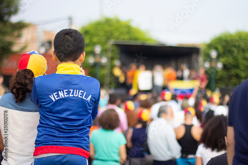 Young boy with Venezuelan pullover watching a stage at Venezuelan protest against Nicolas Maduro photo